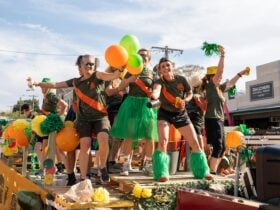 festive float dancers in orange yellow and green for Bridge Road Brewers float
