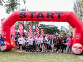 Group of people standing under the start arch waiting to begin the Walk, Run + Roll.