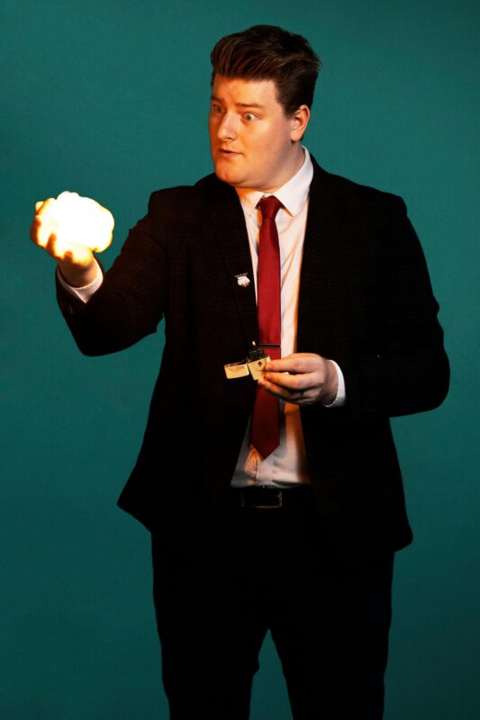 A suit wearing magician with fire ball in his hand