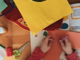 A pair of children's hands doing crafting with textas and orang colour paper