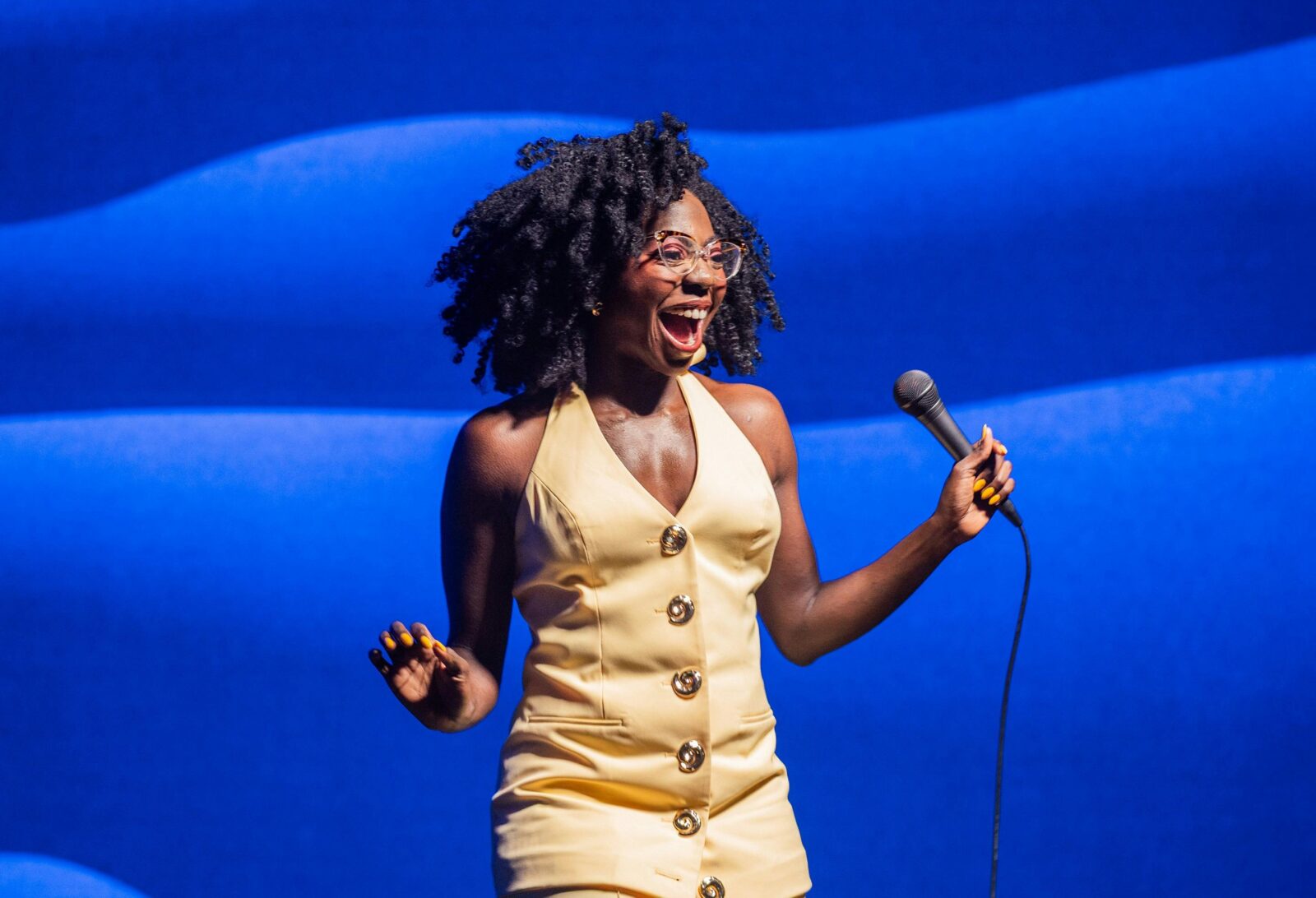 Anisa Nandaula performing on stage holding a microphone.