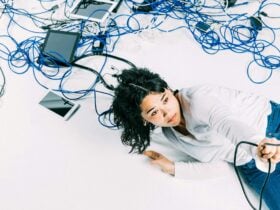 A young woman surrounded by cords and devices hangs on tight to a cord that seems to lead to the sky