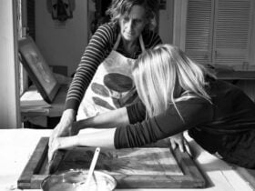Black and white image of two women screenprinting