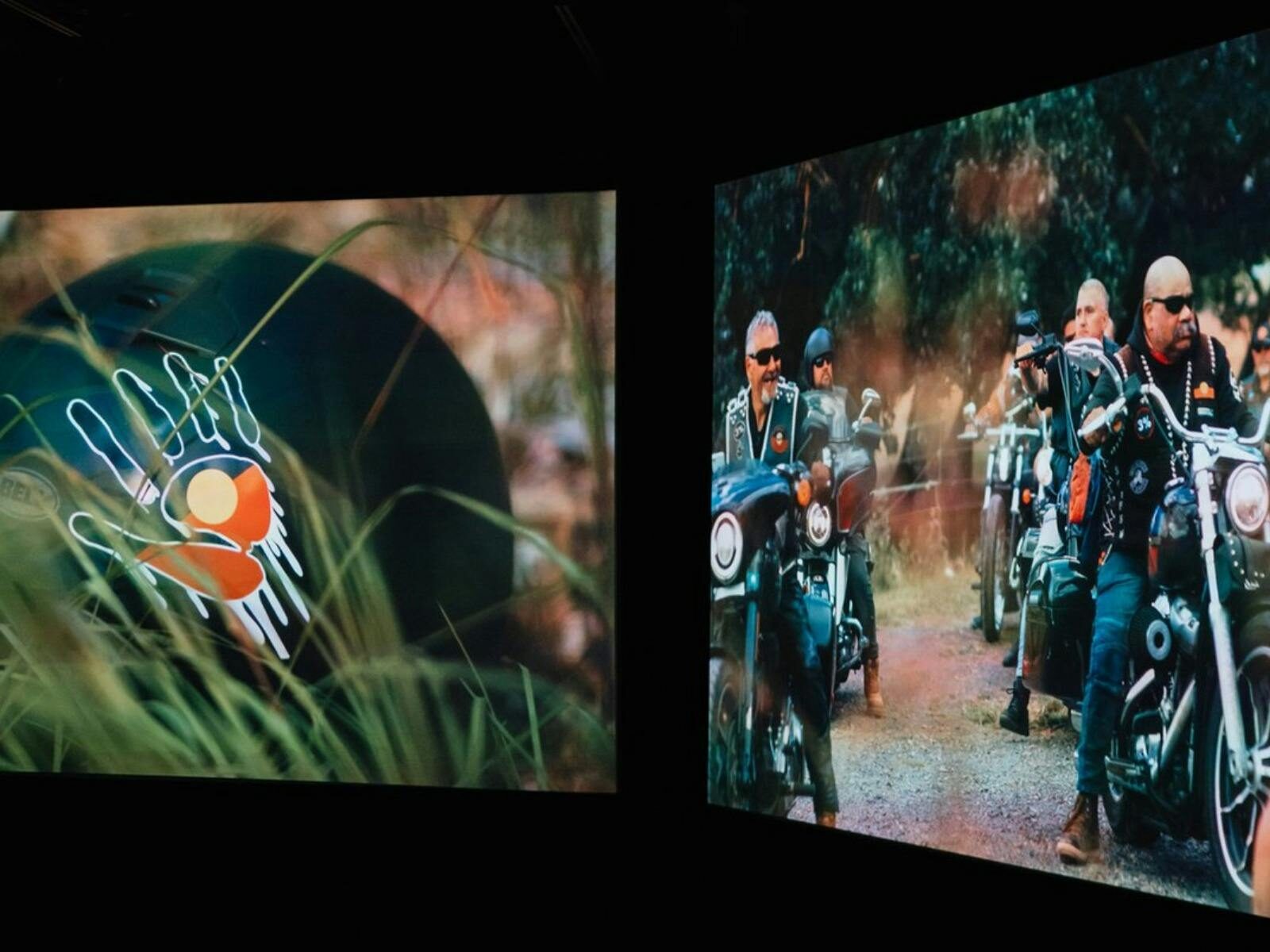 Two-channel video installation showing motorcycles riding bush tracks beside a close-up of grass and