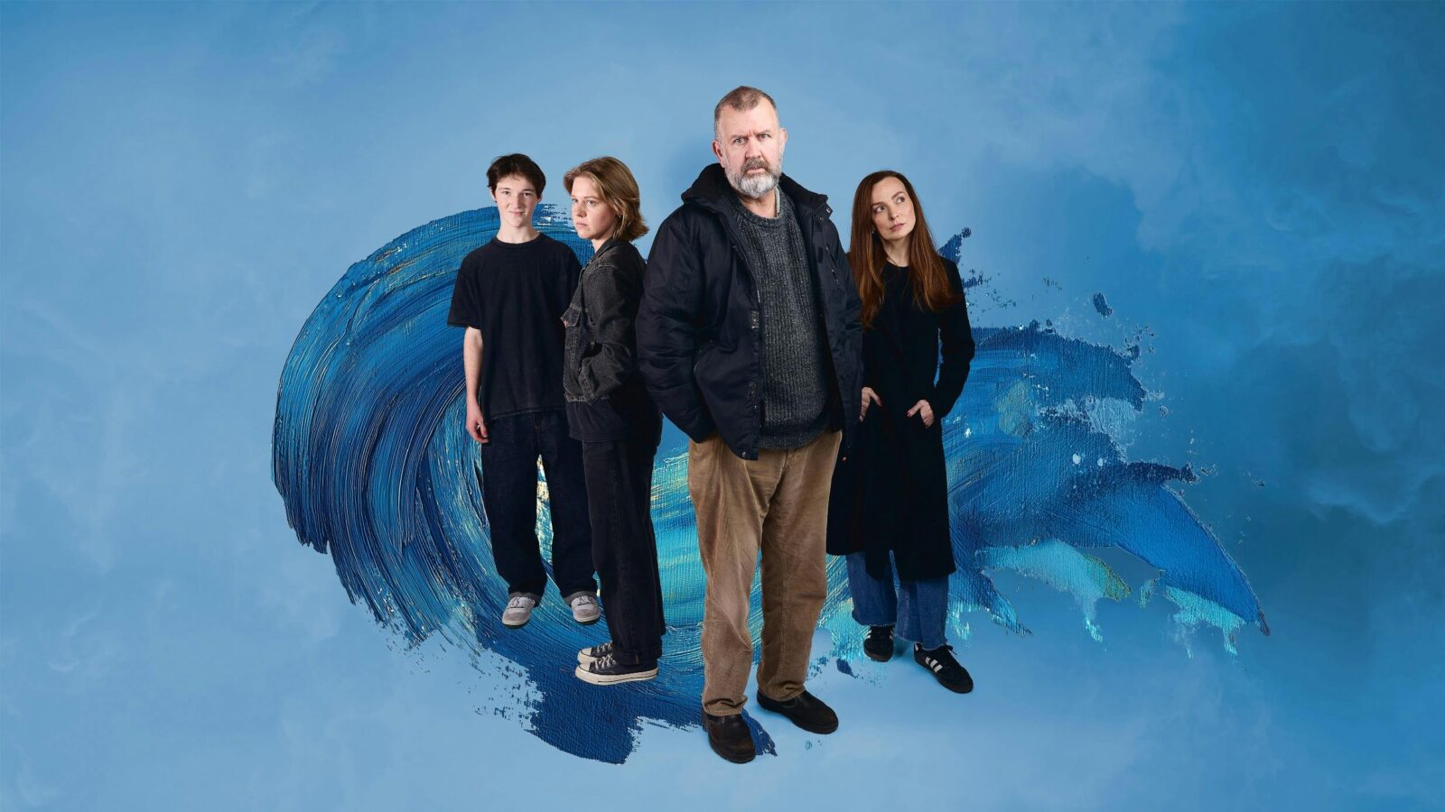 Four people stand grouped against a blue background. They are all looking in different directions.
