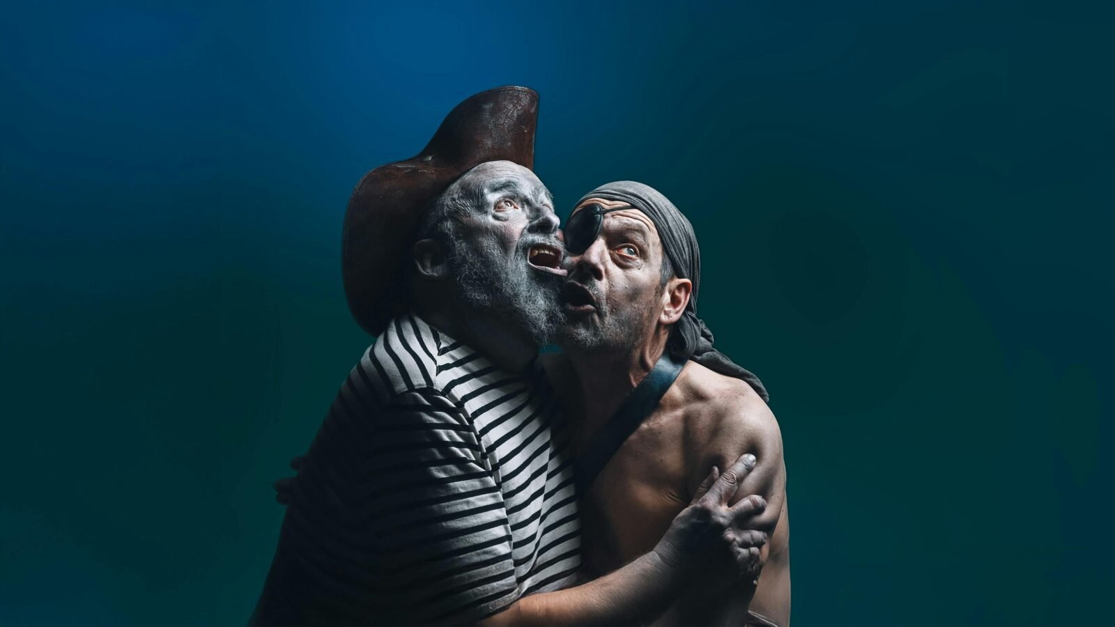 Two ghostly male pirates hug eachother and look at something in the sky.