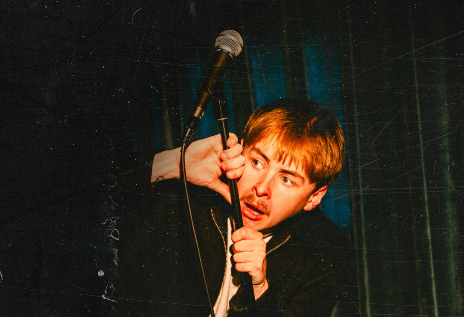 Blake Pavey hiding behind a microphone with scared facial expression.