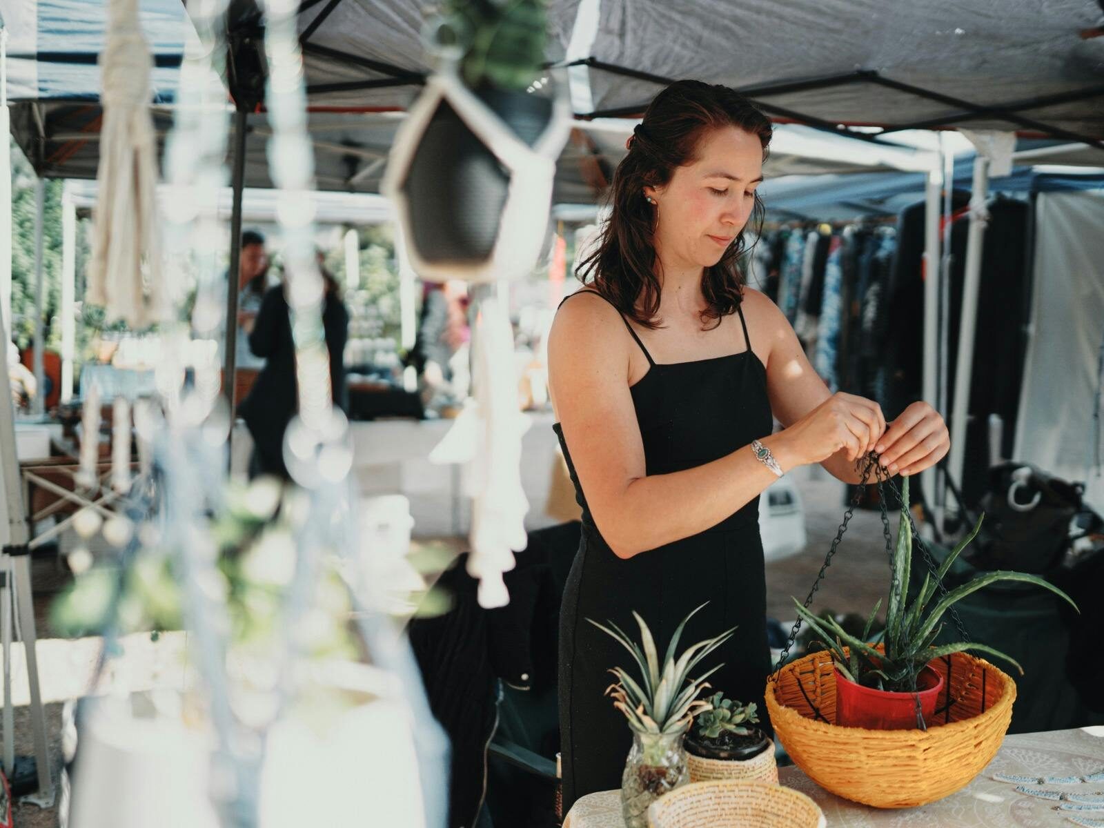 A stallholder at a macrame stall is preparing a plant to hang.
