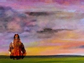 erson sitting on grass facing a colorful sunset sky with purple and orange hues.