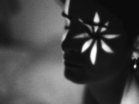 A face in shadow with a flower-shaped light cast over it