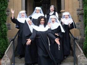 Sarahlouise Younger as Deloris Van Cartier and lead nuns posing in font of Chapel.