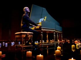 Erin Helyard playing at a harpsichord, surrounded by soft glowing candles