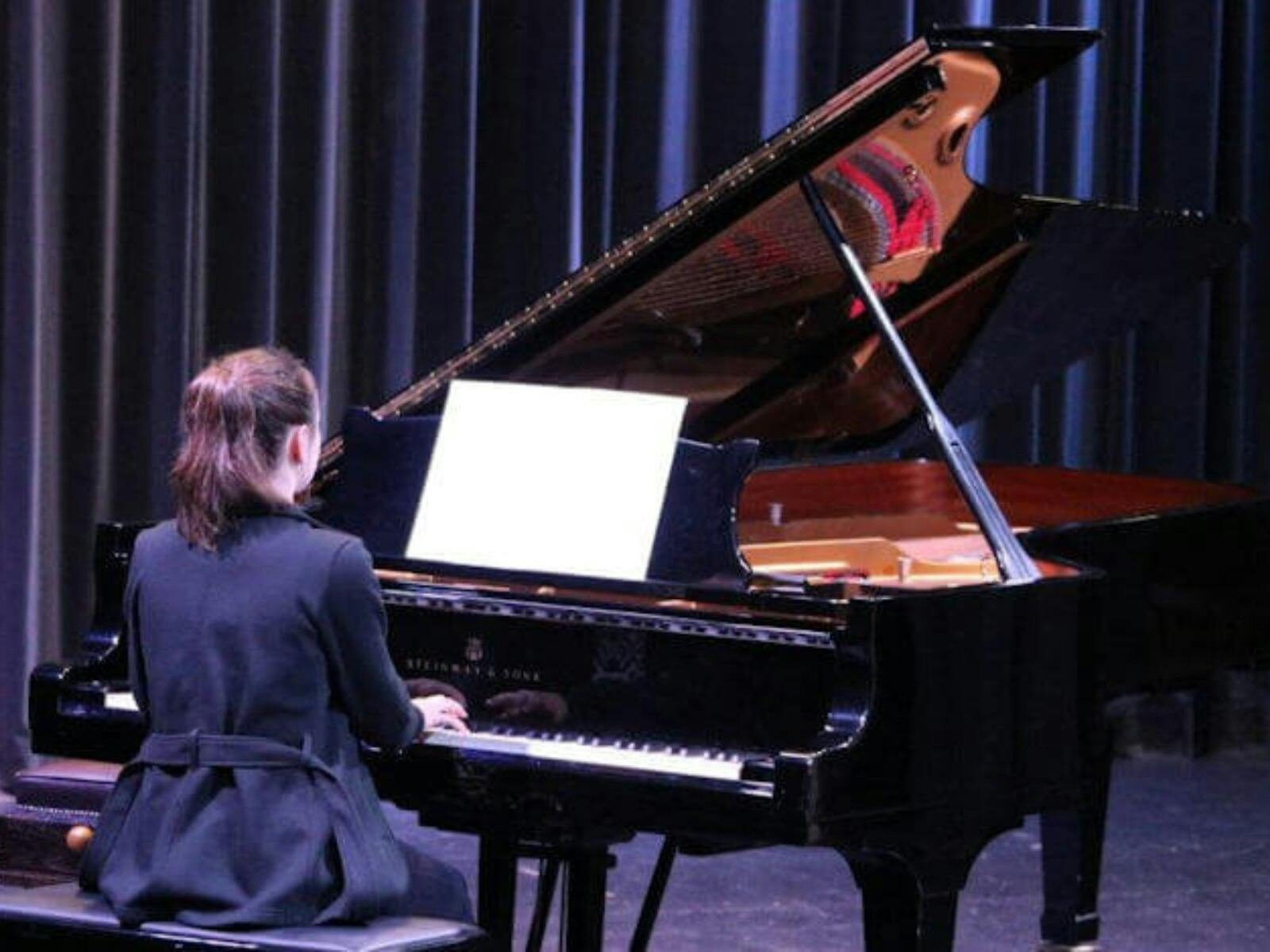 A pianist on stage performing on a grand piano