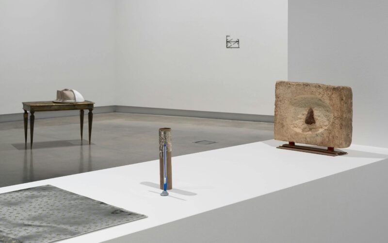 A photograph of a gallery with sculptural objects arranged on a plinth