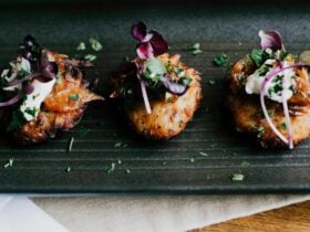 A line of three canapes served on a charcoal coloured plate. These are served as a starter.