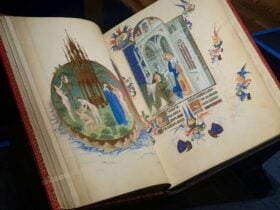 A close-up photograph of an open medieval book with pages displaying ornate images