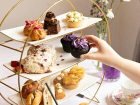 person picking up a purple cupcake from high tea stand