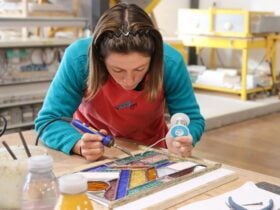 A female student using a soldering iron on her colourful glass leadlight panel