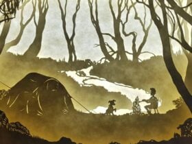 Illuminated paper-cut display of a seated person and dog in a forest