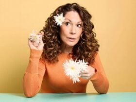 Kitty Flanagan in an orange jumper with white daisies in her hair.