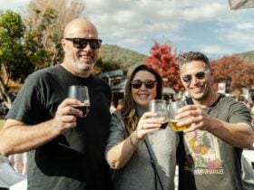 two men and a woman posing with some drinks in hand