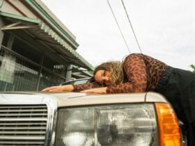 Liv lying on the bonnet of a gold vintage car