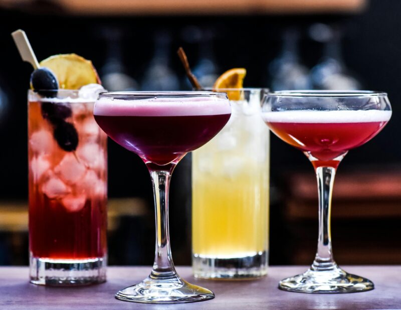 A row of colourful cocktails in different shaped glasses