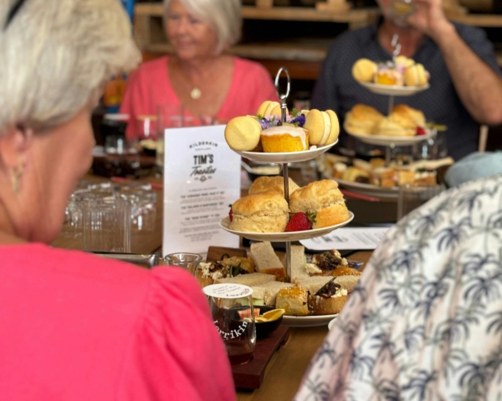 A tower of sweet and savoury treats in the middle of a table that is surrounded by people