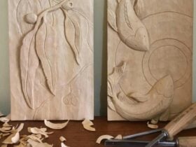 Two wooden relief carvings of gum leaves and koi fish