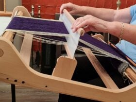 Hands working yarn on a loom
