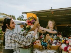 Female market stallholder handing over a bunch of flowers to a young woman