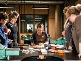 Instructor seated at bench showing participants how to make jewellery