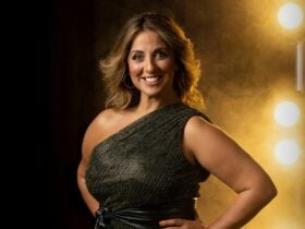 Silvie Paladino on a stage with lights behind her - wearing an off the shoulder green dress