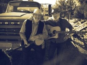 Two Duck Nights holding instruments in front of car.