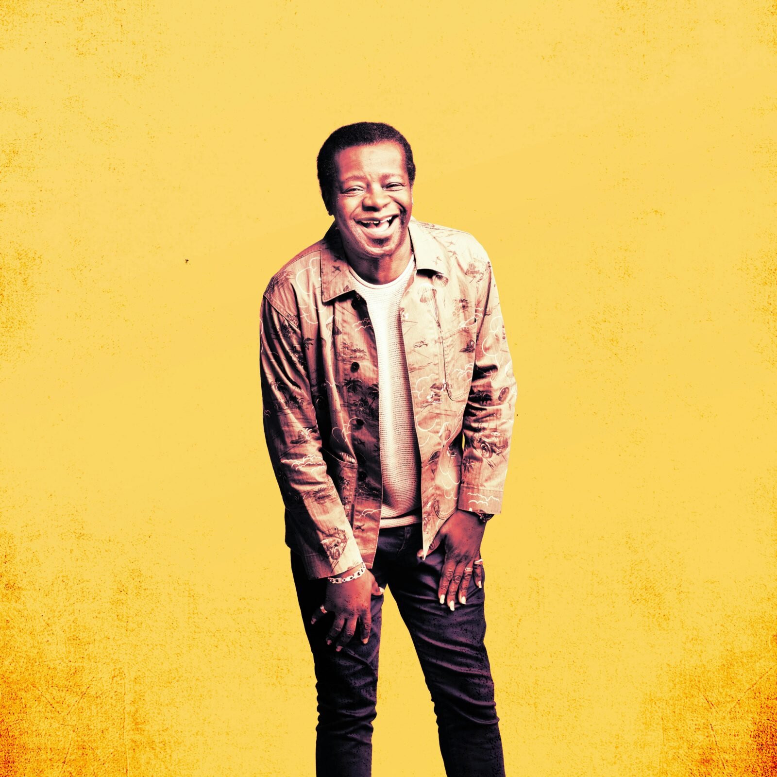 Stephen K Amos posing in front of yellow background.