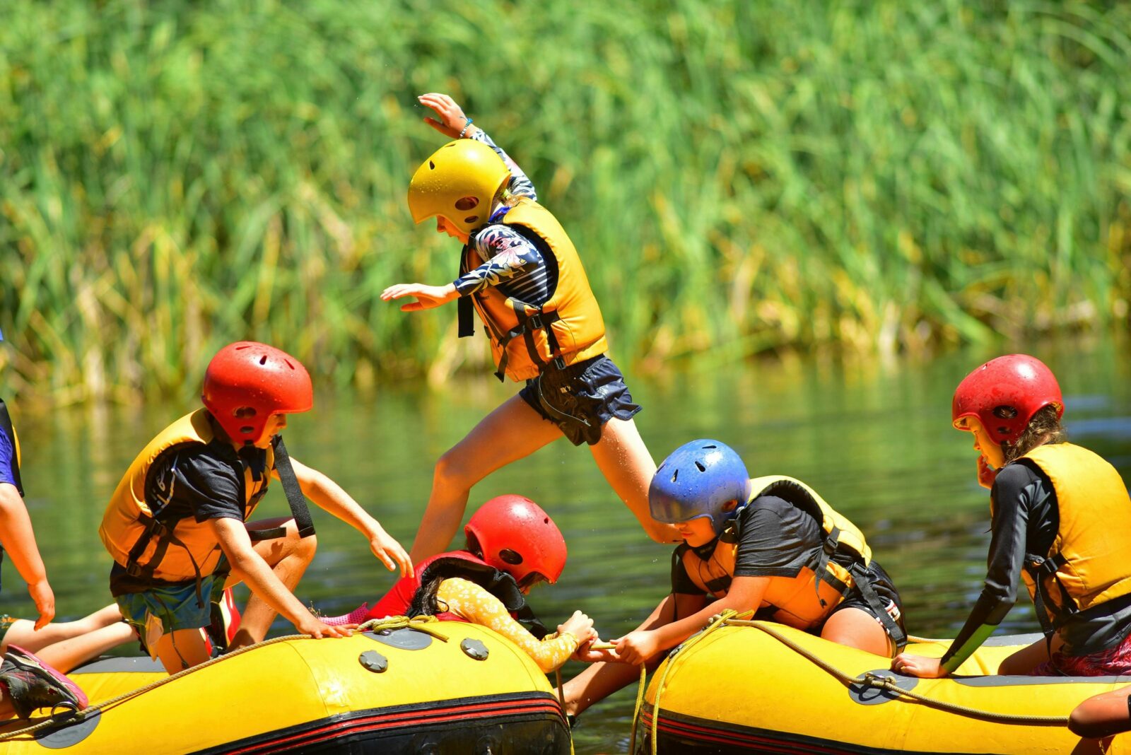 A camper leaps from one white water raft to another