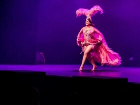 a burlesque dancer dolores with a feather headress performing on stage