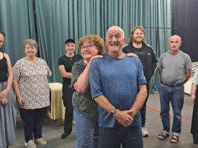 A group of actors stand in a row.