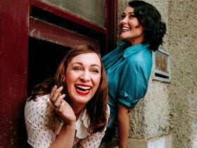 Two young women from 1937 leaning out a window laughing