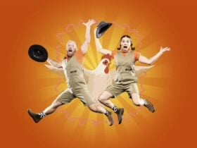 2 performers jumping in the air in front of a chicken and worms.