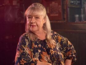 Woman at a bar staring at the camera. She is wearing a floral shirt.