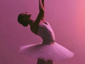Artist of The Australian Ballet wearing a white tutu performs an elegant backâarched pose with arms