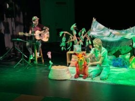 Performer with puppet and guitarist create a playful childrenâs show on stage.