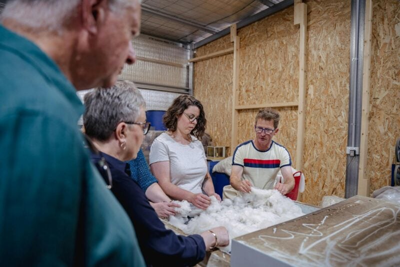 4 people at the carder filling it up with fibre