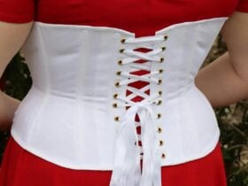 Backshot of a woman wearing a white underbust corset from behind with red top underneath