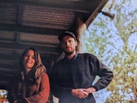 A mand and a woman standing side by side under a tin room