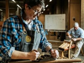 Two men carving wood for chairs in a workshop