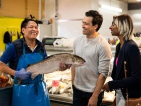 Two people interacting with a stall owner holding a fish at St Albans Market.
