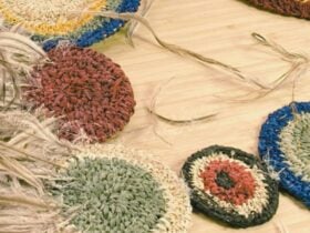 Circular woven pieces in various colors arranged on a light wooden surface, with loose fibers and na