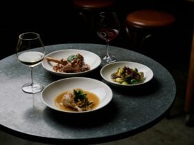 Three round white plates with winter menu dishes on a silver table